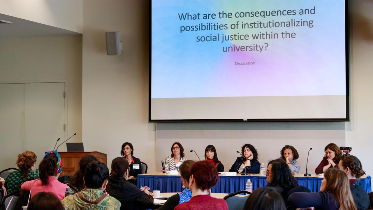 Attendees engage in dialogue with panelists at the "Administration and Diversity in the Public University: A Feminist Conversation Symposium" on April 4. Photo: Scott Tsuchitani Photo: audience view of panelists beneath slide that reads, "What are the consequences and possibilities of institutionalizing social justice within the university?"