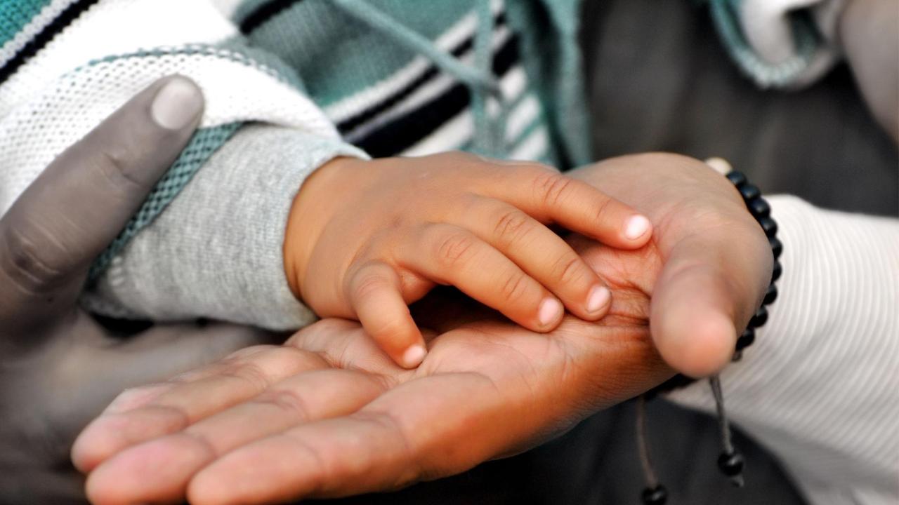 Adult holding child's hand