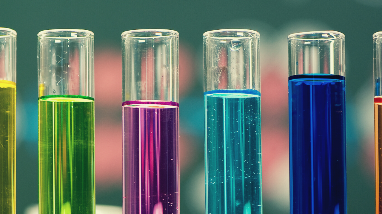 Six test tubes filled with six different colors of liquid: from left to right, yellow, green, purple, turquoise, blue, orange