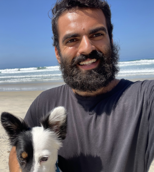 Medium close up of Julian Haddad and black and white dog at the beach