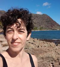 Portrait of Caro Novella, medium close-up, direct sunlight, sea and mountains in background