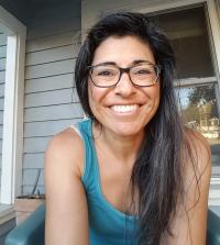 Headshot of Coco Herda smiling, seated on porch