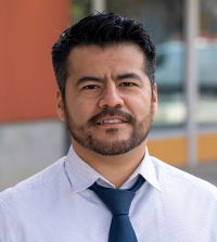 Headshot of JC Garcia Sanchez, in dress shirt with blue necktie