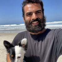 Medium close up of Julian Haddad and black and white dog at the beach