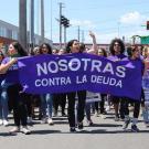 Women of Colectiva Feminista en Construcción marching in street with banner that reads "NOSTORAS CONTRA LA DEUDA"