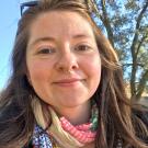Portrait of Colleen Sargent, wearing a scarf and posed against a blue sky
