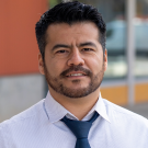 Headshot of JC Garcia Sanchez, in dress shirt with blue necktie