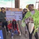 Four young people gather around a poster at a San Francisco Municipal Transit Authority community event