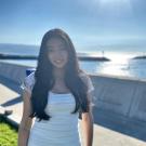 Photo of Serena Broome, medium long shot, wearing white dress, backlit by sun