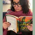 Dr. Hernandez reads her book, Fresh Banana Leaves, dressed in large, dark frames, a rose scarf, and dark nails.